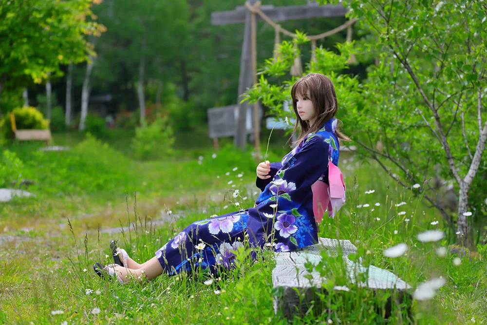 Life-size Japanese love doll wearing a yukata in a natural outdoor setting