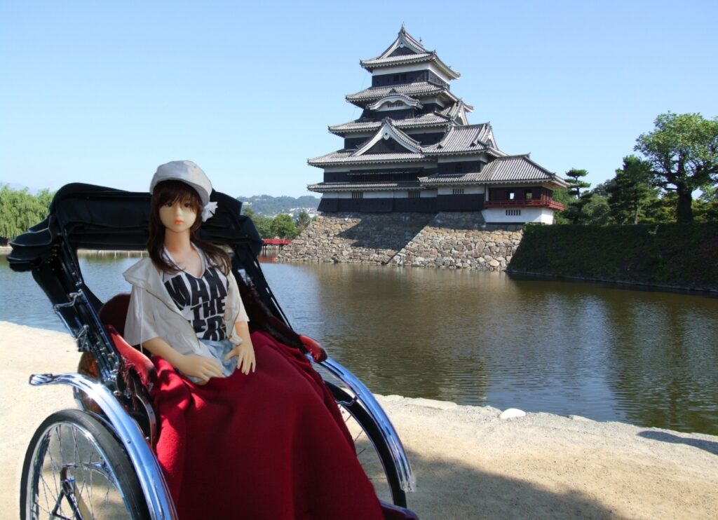 Orient Industry love doll seated in rickshaw in front of traditional Japanese castle