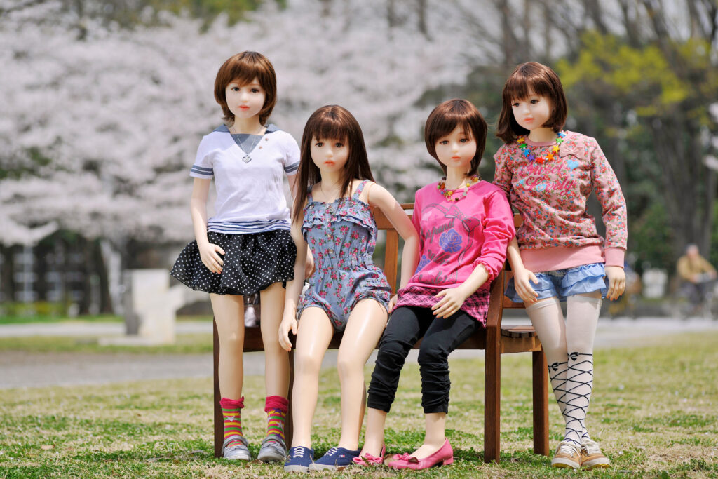 Orient Industry Japanese love dolls sitting in a park with cherry blossoms