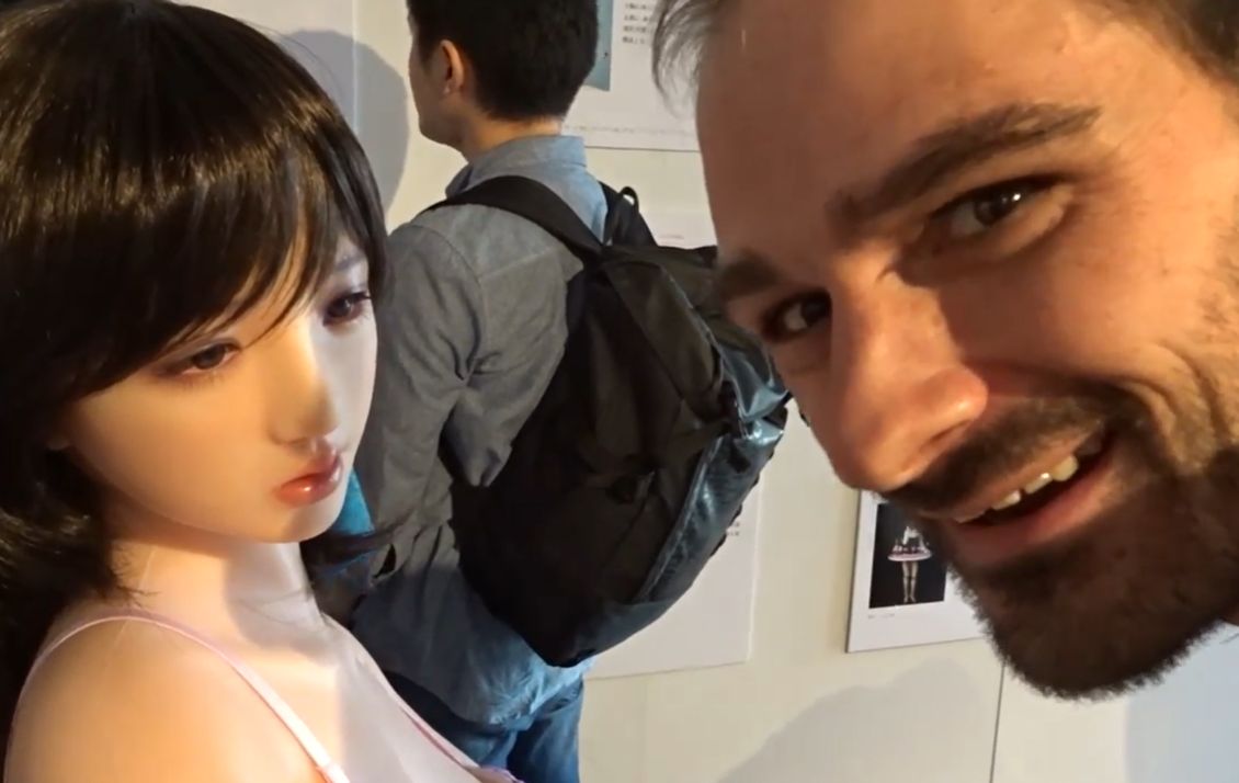 Overseas visitor reacting to a realistic Japanese love doll face at an exhibition