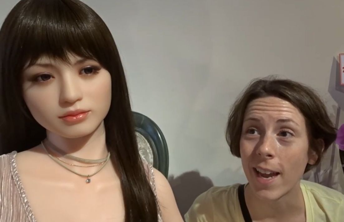 Overseas visitor showing interest in a realistic Japanese love doll at an exhibition
